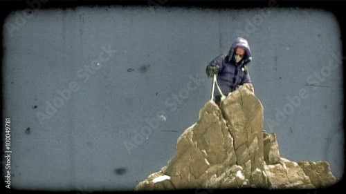 Climber mounts rocky peak. Vintage stylized video clip. photo