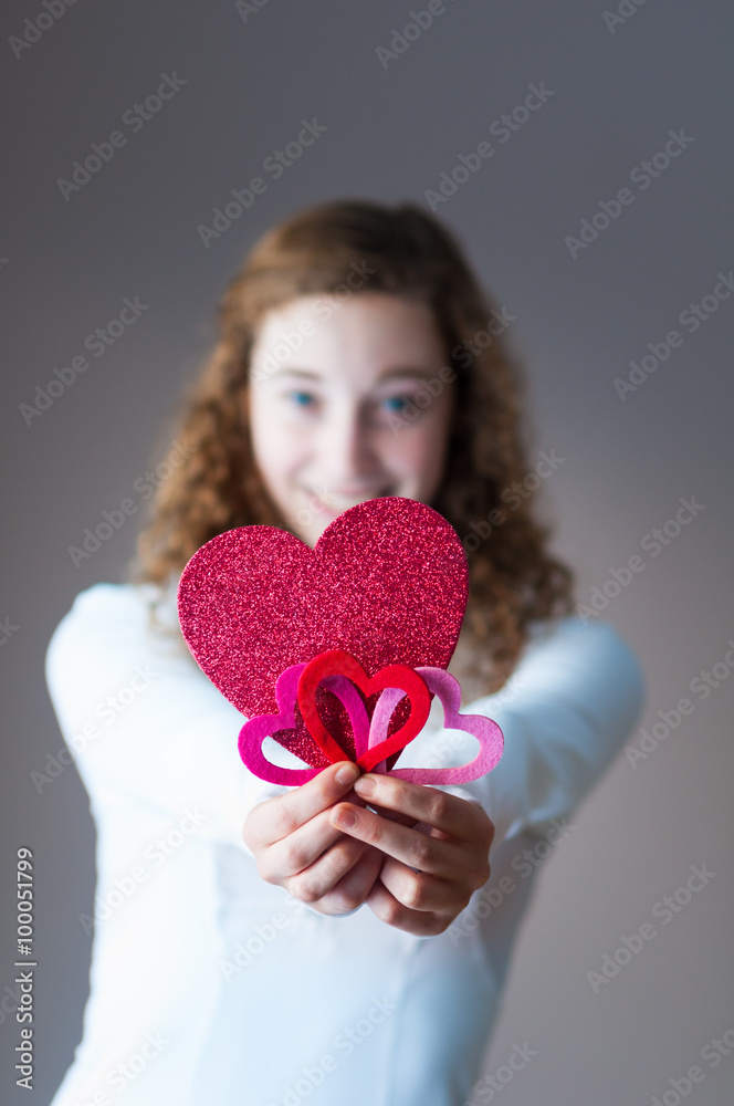 cute teengage girl holding out a bunch of valentine hearts