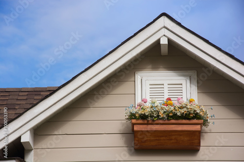 Wooden window with flower at the roof of the house.