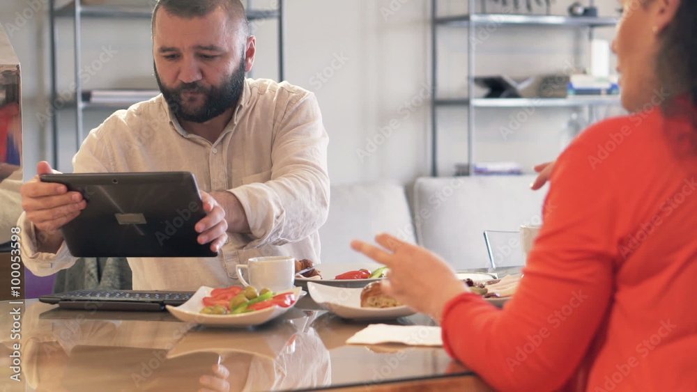 Young couple using modern tablet during breakfast at home
Young couple using modern tablet during breakfast at home