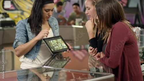Associate at a recreational marijuana shop using a tablet to show product to customers