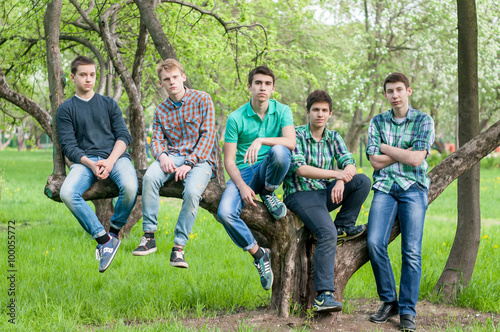 group of guys posing against a tree after school