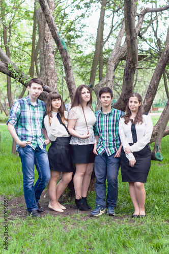 Five young friends happy graduates posing in the summer park