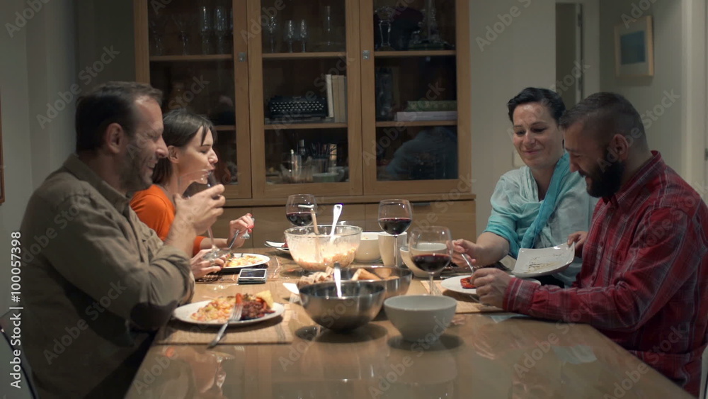 Young group of friends talking and eating dinner at home
