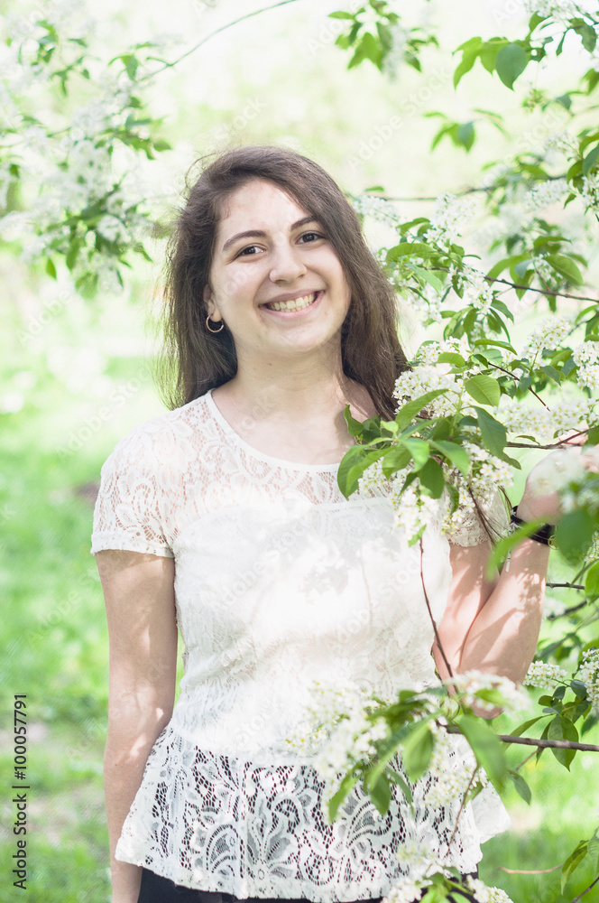 Young girl walking in the lush garden with flowers