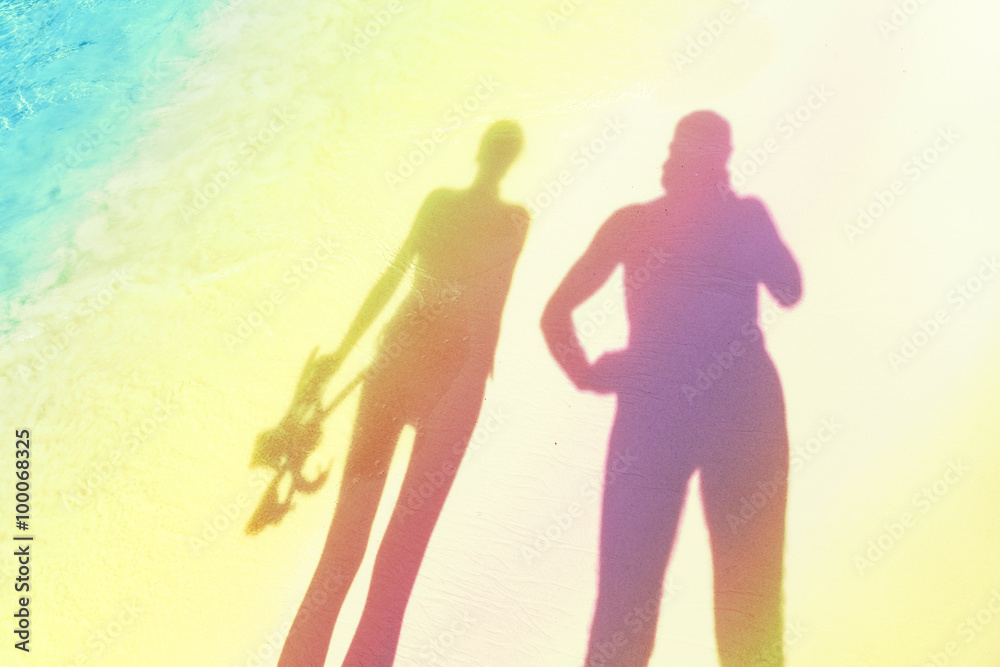 Stylized silhouettes of woman holding snorkeling equipment and man on the beach.