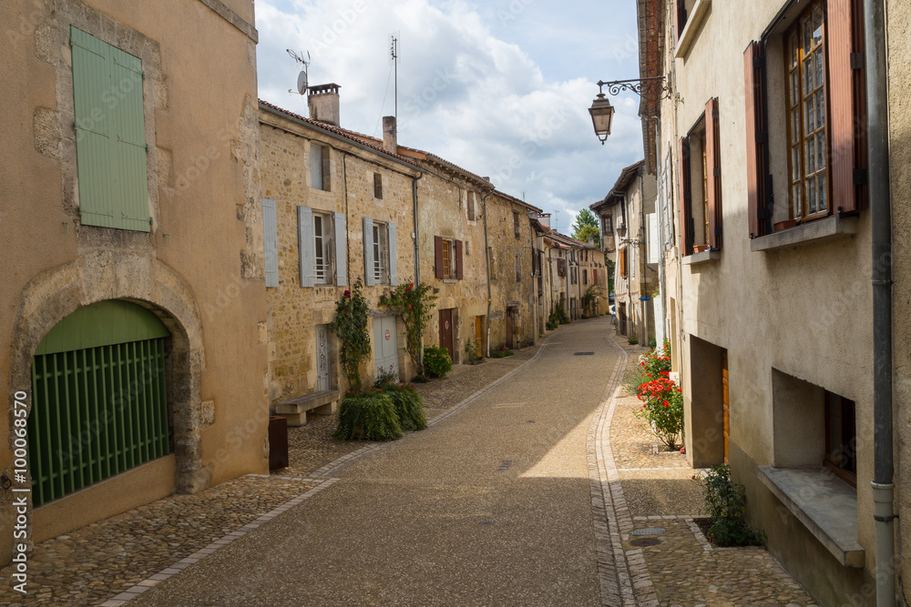 typical French narrow street with ocher colored facades of old houses in small village in Aquitaine 