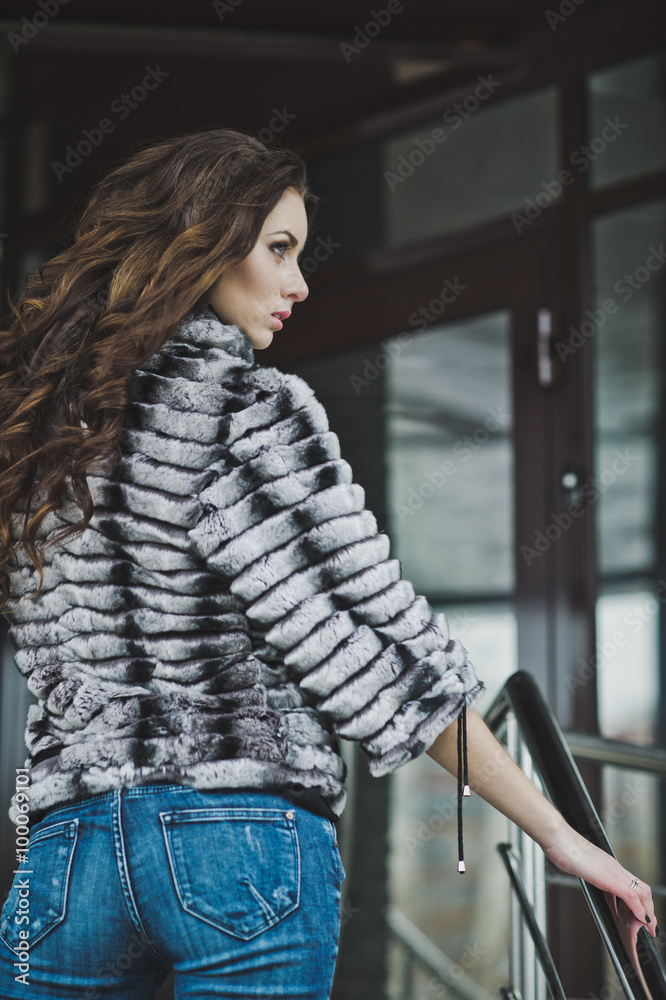 A slender girl in a coat and jeans near the stairs 4998. A slender girl in a coat and jeans near the stairs 4998.