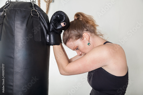 A young woman leans hands of black punching bag © edojob