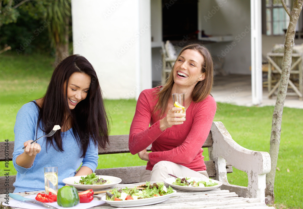 Two female friends laughing and having lunch together Two female friends laughing and having lunch together