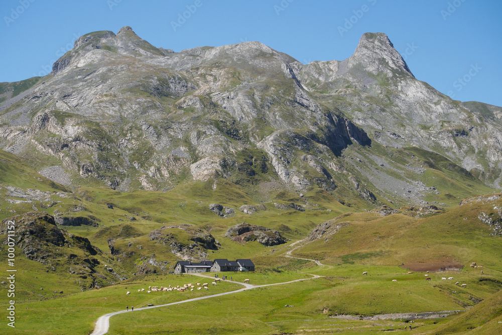 rocky ridge of Pyrenees in France at border with Spain with pasture and chalet below the hills rocky ridge of Pyrenees in France at border with Spain with pasture and chalet below the hills