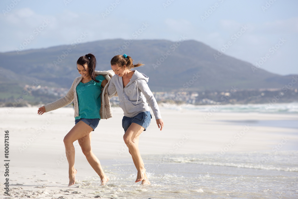 Two women friends walking together on the beach Two women friends walking together on the beach