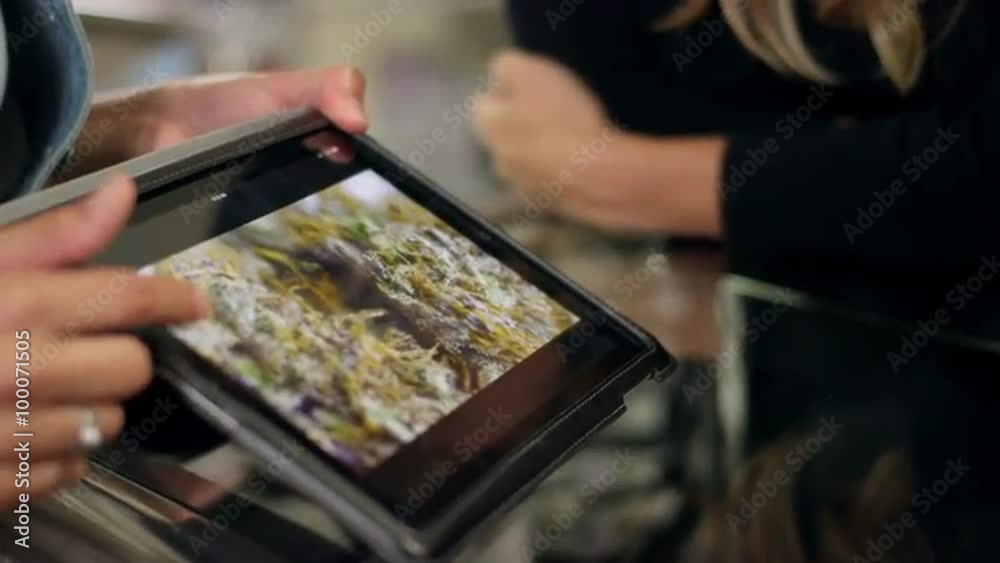 Close up of an associate at a recreational marijuana shop pointing to their product on a tablet