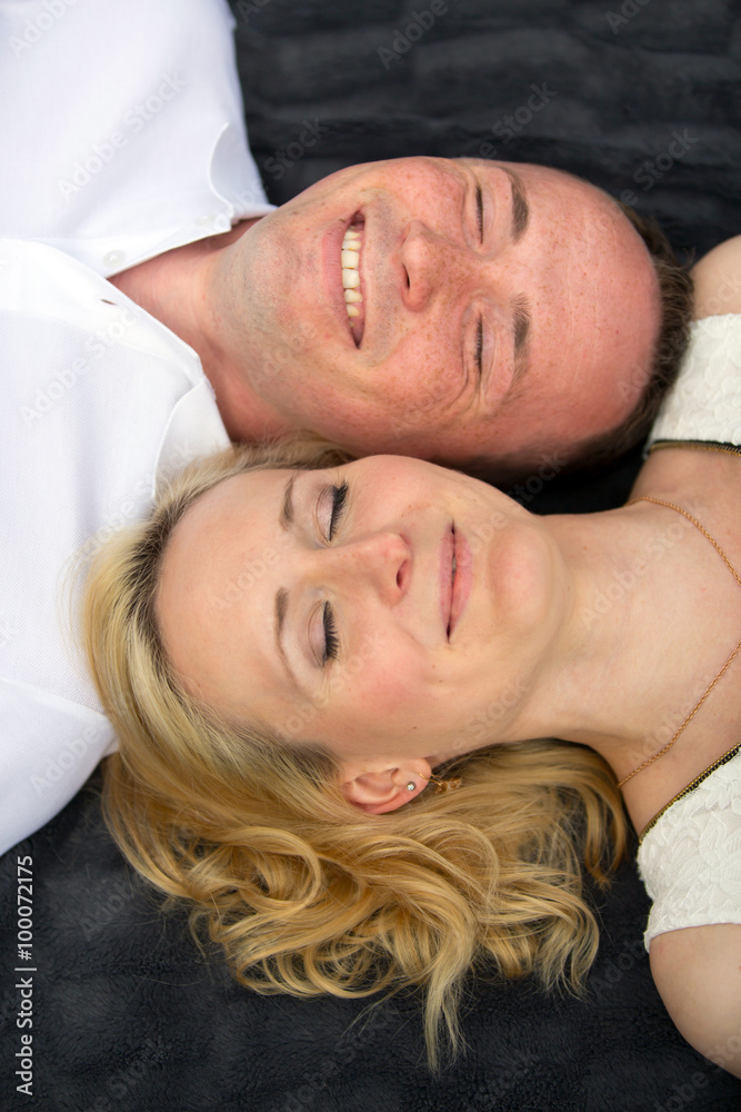 Happy and smiling couple with closed eyes lies on a gray plaid Happy and smiling couple with closed eyes lies on a gray plaid