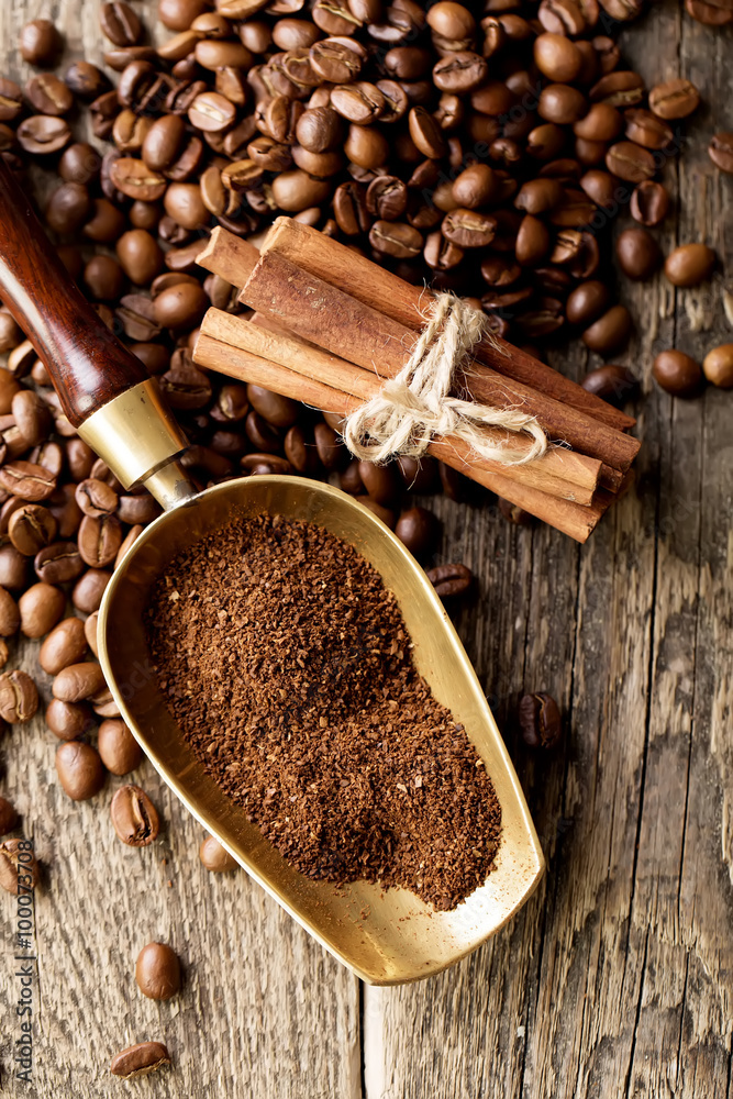 ground coffee in scoop and coffee beans on a wooden background