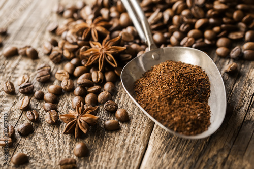 ground coffee in scoop and coffee beans on a wooden background