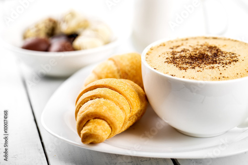 Hot cappuccino and pastries on white wooden boards