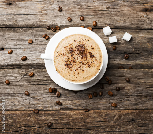 Close-up of coffee cup with roasted coffee beans on wooden backg