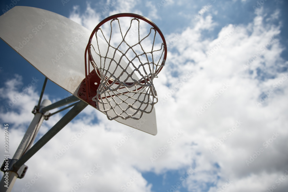 basket ball hoop outside against a blue sky with clouds