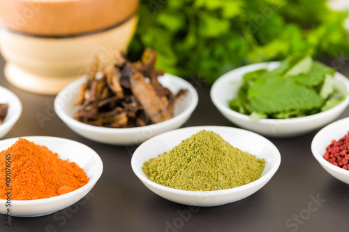 Beautiful colorful display of different spices green orange brown in white bowls  shot from above side angle  grey background