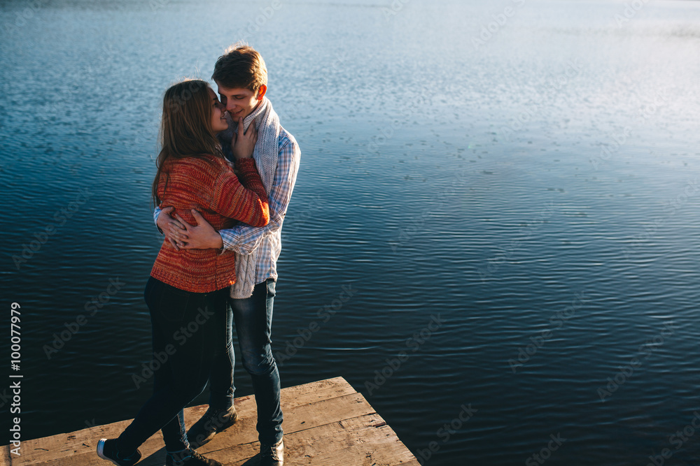 Couple hugging each other on a pier by a river with copy space