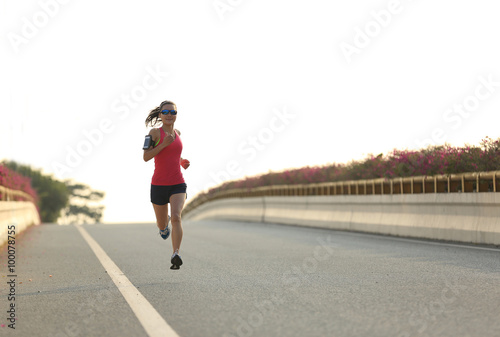 young woman runner running on city bridge road © lzf