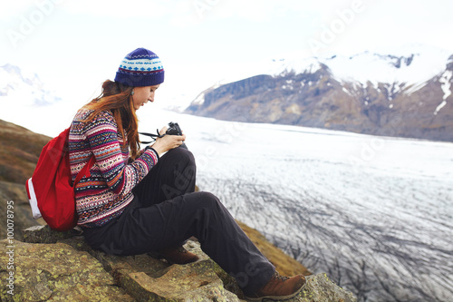 Young woman with backpack sitting near glacier in Iceland. Backp photo