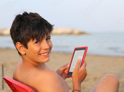 smiling boy with hair blacks reads an e-book