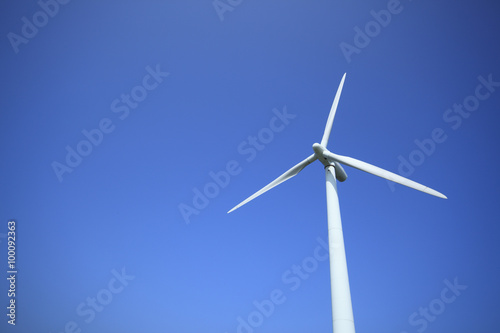 Power generating wind turbine on blue sky with sun. © MP_P