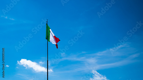 Italian flag waving in the sky with clouds, Monte Grappa, Italia.