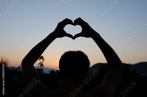  Young man shapes heart with sunset