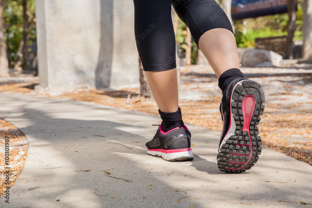Running feet of young woman going by concrete trail in the park Running feet of young woman going by concrete trail in the park