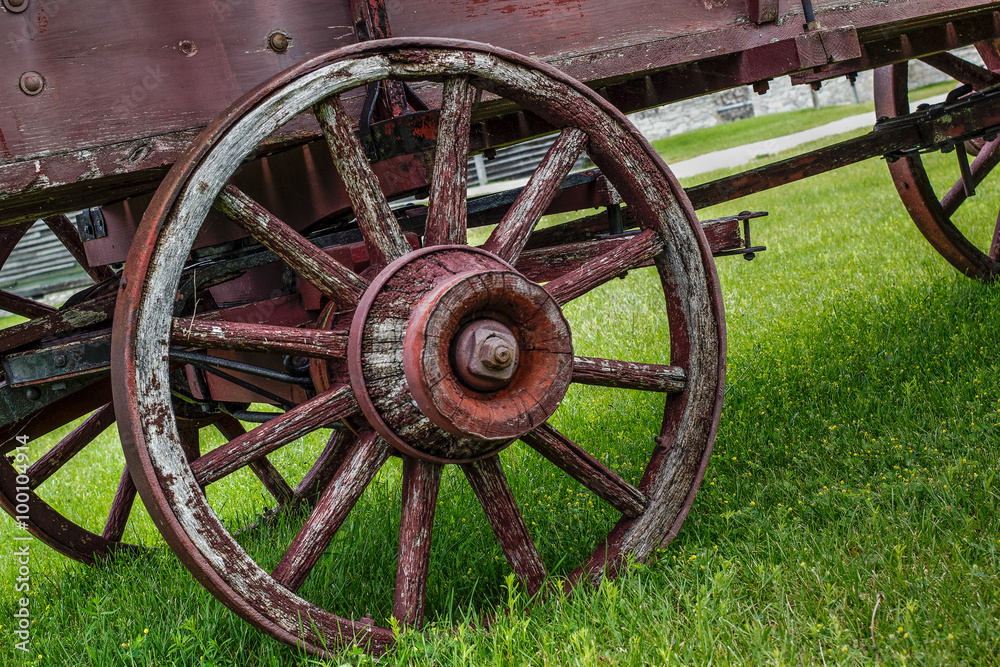 Pioneer Transportation. Wooden wheel on a weathered and worn covered wagon.