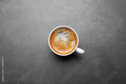 Cup of coffee on grey background, top view
