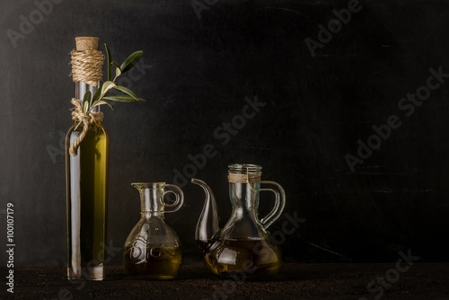 Bottle and glass jars of extra virgin olive oil on rustic background