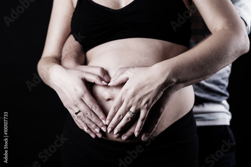 Heart shaped hands of pregnant woman and her husband
