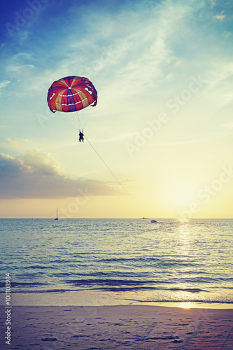 Vintage stylized picture of parasailing at sunset, summer adventure concept, Malaysia.