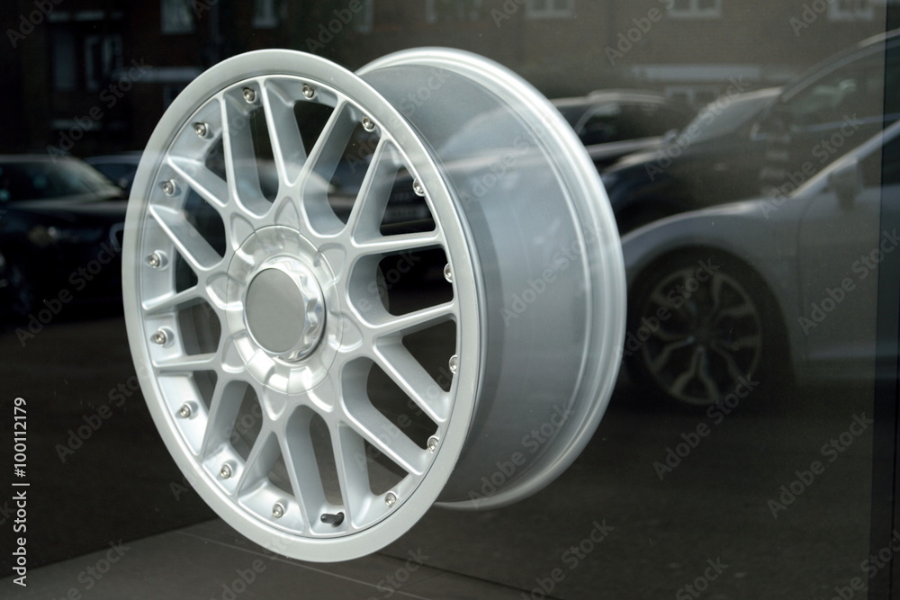 Alloy wheels in shop window with cars reflected on glass in background