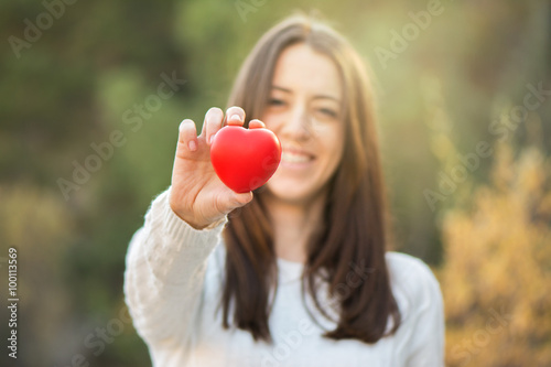Portrait of beautiful young woman holding red heart