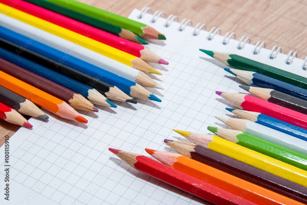 Set of colorful pencils lying in row on white paper sheet Set of colorful pencils lying in row on white paper sheet
