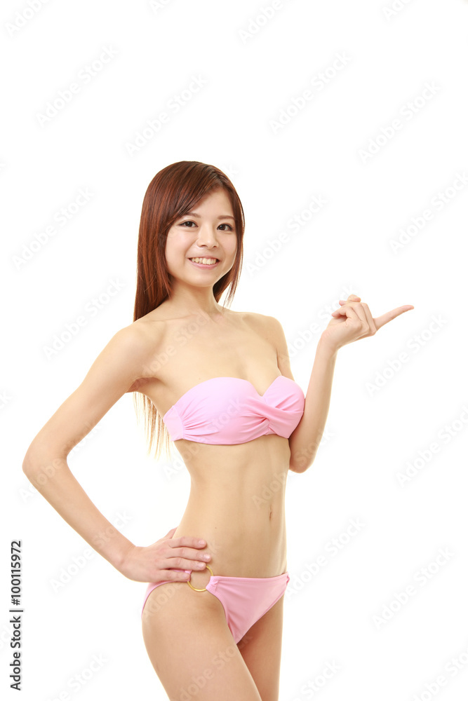 young Japanese woman in a pink bikini presenting and showing something  Photos | Adobe Stock