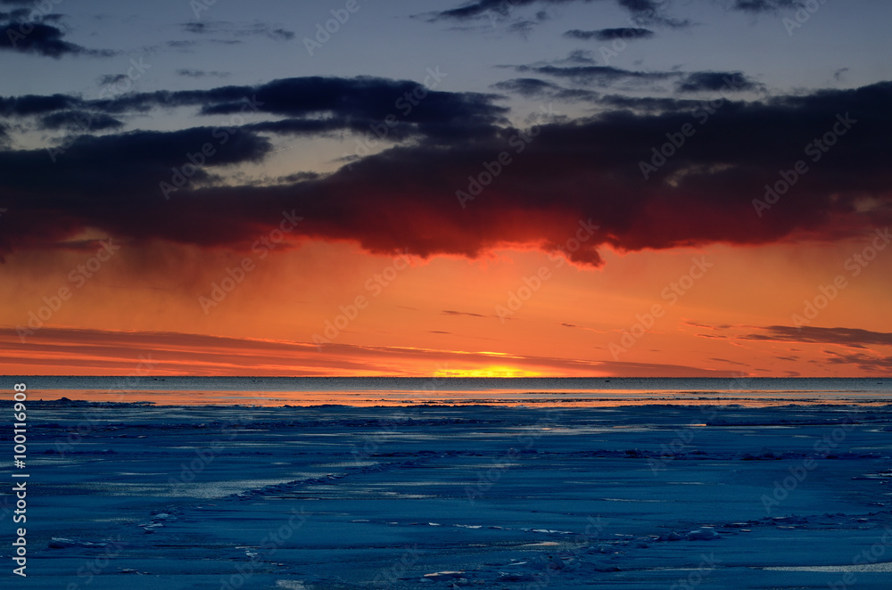colorful sunset at the snowy Baltic sea shore