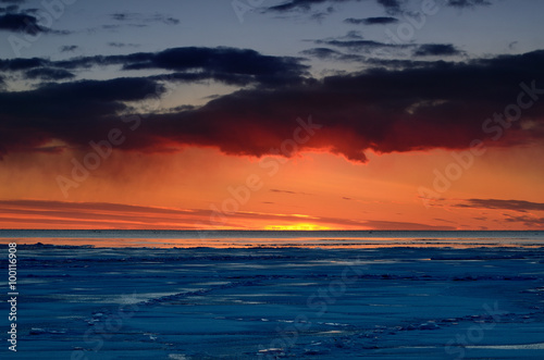 colorful sunset at the snowy Baltic sea shore