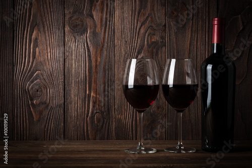 Red wine bottle and two glasses of wine on the dark wooden backg © ffphoto
