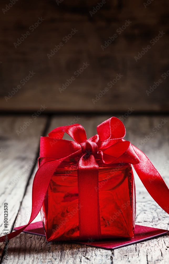 Red gift box tied with a scarlet ribbon with a bow on the old wo Stock ...