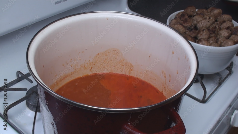 Big red pot of tomato sauce being prepared for home made pork and beef meatballs. Big red pot of tomato sauce being prepared for home made pork and beef meatballs.