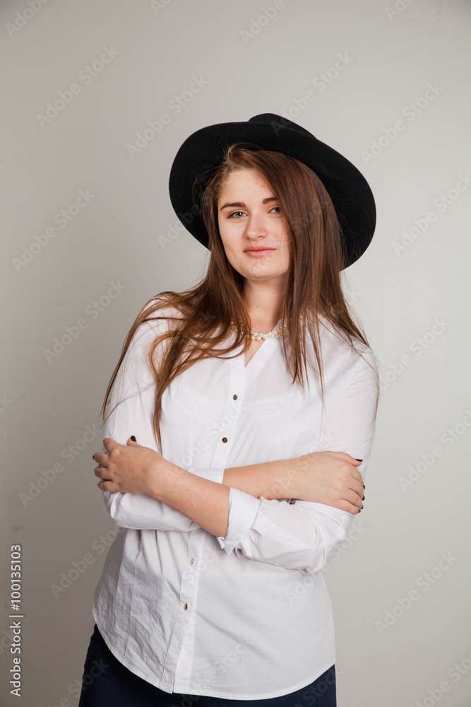 Awesome Caucasian attractive shy sexy female model with brunette hair posing on table in studio, wearing formal suit and hat, isolated on white background Awesome Caucasian attractive shy sexy female model with brunette hair posing on table in studio, wearing formal suit and hat, isolated on white background