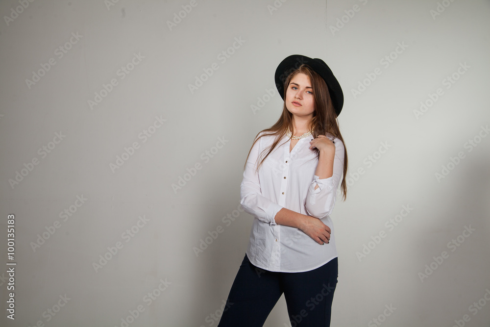 Awesome Caucasian attractive shy sexy female model with brunette hair posing on table in studio, wearing formal suit and hat, isolated on white background Awesome Caucasian attractive shy sexy female model with brunette hair posing on table in studio, wearing formal suit and hat, isolated on white background