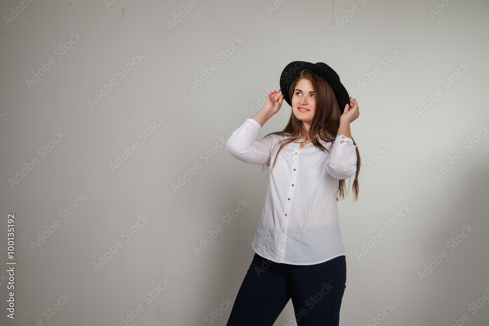 Awesome Caucasian attractive shy sexy female model with brunette hair posing on table in studio, wearing formal suit and hat, isolated on white background Awesome Caucasian attractive shy sexy female model with brunette hair posing on table in studio, wearing formal suit and hat, isolated on white background