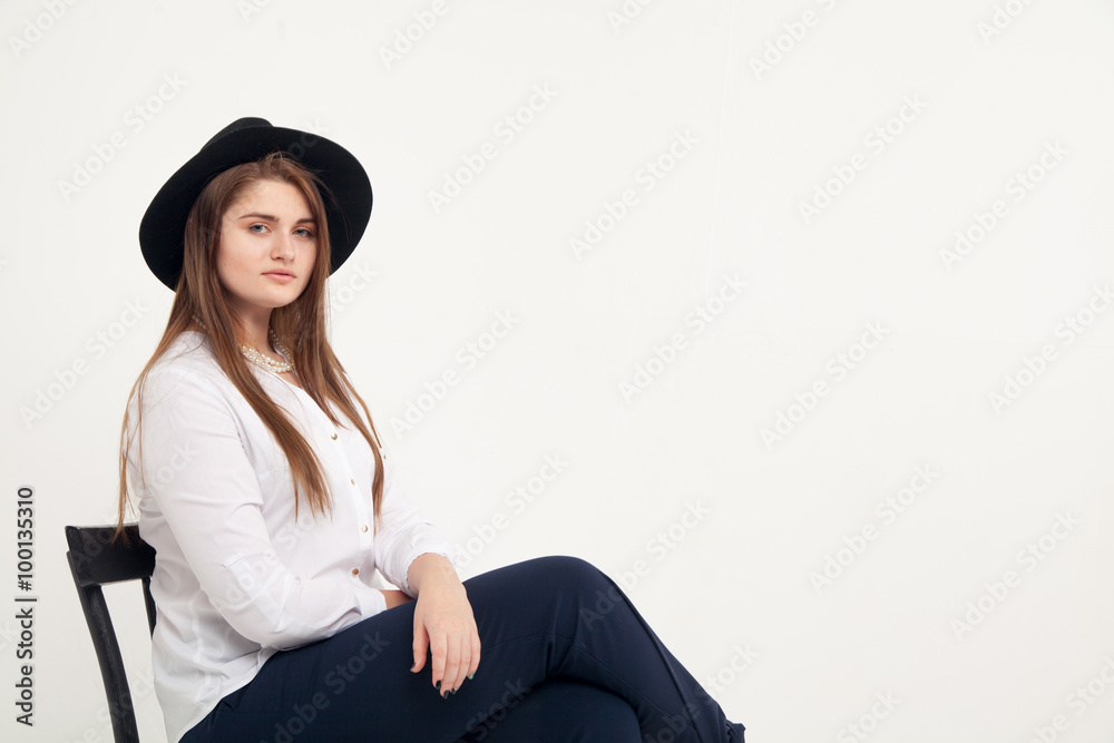Awesome Caucasian attractive shy sexy female model with brunette hair posing on table in studio, wearing formal suit and hat, isolated on white background Awesome Caucasian attractive shy sexy female model with brunette hair posing on table in studio, wearing formal suit and hat, isolated on white background